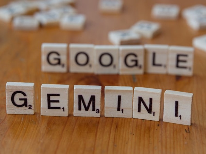 A wooden table topped with scrabble tiles spelling google, genni, and